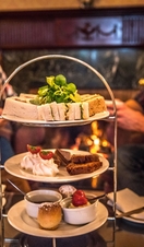 Couple sat drinking tea in fron tof an afternoon tea spread