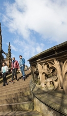 Three men walking down stone steps of a monument