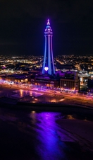 Seaside town at night with tower lit up.