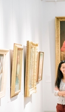 An asian woman and teenager looking at paintings in gallery