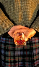 Scotsman with glass of whiskey held behind his back