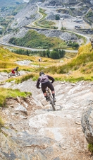 People mountain biking down a steep hill. 