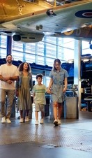 Family of four walking beneath a biplane on display