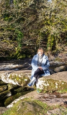 Lady sitting on rock as boy runs by