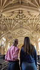 Two women look up towards an ornate ceiling