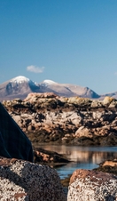 A woman sitting on a rock wrapped in a tartan blanket