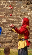 A juggler in costume juggling balls at Castell Coch in Wales