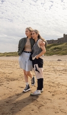 Two women hugging on the beach near a castle