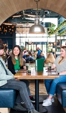 Two women and a man sit in a booth at a restaurant