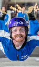 A person riding the iFLY Indoor Skydiving experience with a crowd of people watching behind