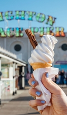 Close up of person holding ice cream cone on pier