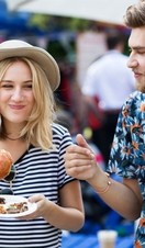 Couple eating burgers at food market.