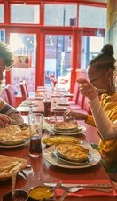 Two young men and one young woman, eat an Indian meal