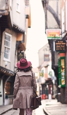 Woman wearing trench coat and pink hat walking 