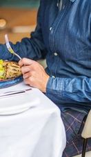 A man sitting at a restaurant table with a charcuterie salad and a cocktail.