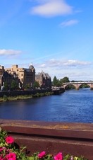 A view across a wide river to a church in the summer