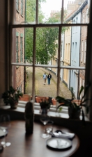 A man and a woman walk along a cobbled street seen through a window