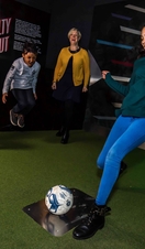 A group of people taking part in a penalty shootout exhibit in the National Football Museum in Manchester