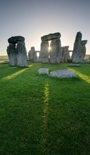 Large stone pillars arranged in circle on grass. Sunset