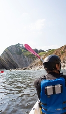 People kayaking along the shores of coastline