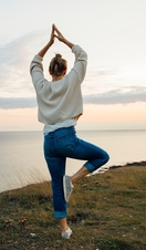 Rear view of woman in yoga pose standing on top of the cliff