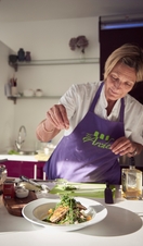 Blond woman wearing purple apron preparing food in kitchen