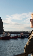 A woman, wearing sunglasses, looking out to see the harbour