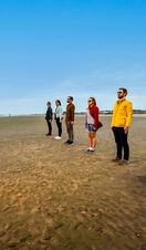 People standing beside Antony Gormley's Another Place sculptures on Crosby Beach, Liverpool