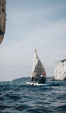 Person in canoe navigating coastline with cliffs in the background