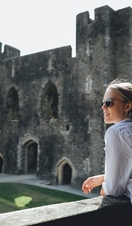 A woman in sunglasses looking out across Caerphilly Castle