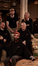 Staff posing on top of coffee bean sacks at Dear Green Coffee, Glasgow