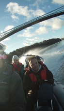 A group of people passing under an iron bridge on a speedboat in Snowdonia/Eryri National Park
