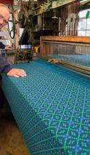 A weaver displaying a working weaving loom at Trefriw Woolen Mills in Snowdonia/Eryri National Park, Wales