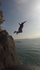 A group of people jumping from low cliffs into the sea near Snowdonia/Eryri National Park