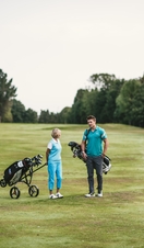 A man and a woman carrying golf clubs on Exeter Golf and Country Club Course