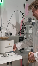 A man in a lab coat using a distillery machine in Exeter's Quayside Distillery