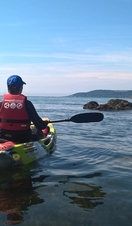A person paddling a kayak off the coast of Mount Batten in Plymouth