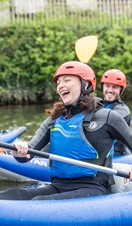People smiling and laughing while kayaking down a river in Chester