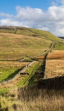 30.10.21 Kingsdale, North Yorkshire, UK. Woman wearing purple jacket and carrying a blue rucksack walking towards the Ingleton waterfall trail in nort