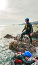 People coasteering off rocks into the ocean.