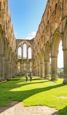 Two people walking between outdoor stone pillars
