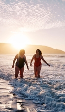 Open water swimmersby the shore at sunset.