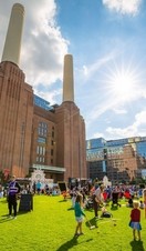 An outside shot of Battersea Power Station in the sun, surrounded by families and groups of people