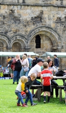 Groups of people eating and shopping outside Kirkstall Abbey