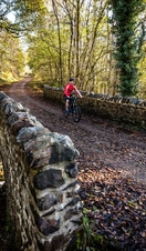 Cyclist in red vest riding along path beside loch