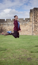 Young woman hovering on a broomstick in the Outer Bailey of Alnwick Castle