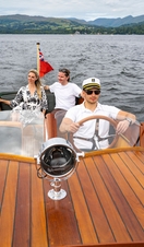 A man and a woman on a boat driven by a skipper on a lake