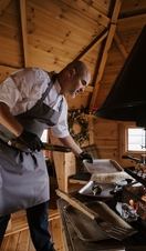 A chef cooking inside a quaint barbecue hut.