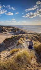 Woman walking along sand dunes at Formby beach