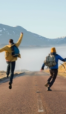 Hikers celebrating along a country road. Mountains ahead